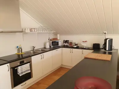 a kitchen with white cabinets and a black counter top at Lauvøy Feriesenter in Askøy