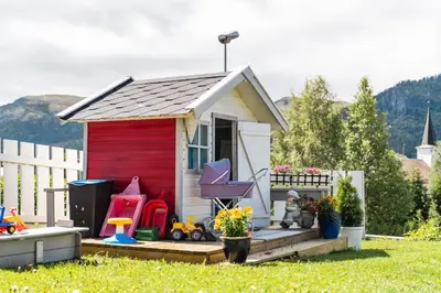 a small red and white shed in a yard at Sandli Overnatting in Alvdal