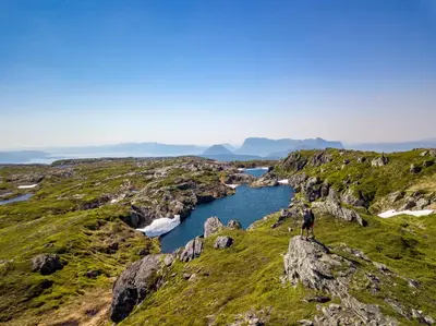 a man standing on top of a mountain overlooking a river at Bosdalhuset in Lavik
