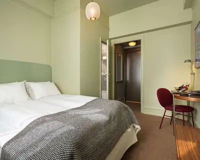 a bedroom with a bed and a desk and a table at Grand Hotel Terminus in Bergen