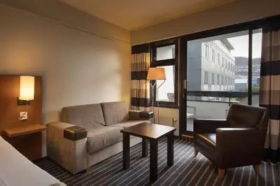 a hotel room with a couch and a chair and a window at Scandic Sunnfjord Hotel & Spa in Førde