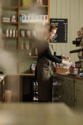 a woman standing in a kitchen preparing food at Hotel Brosundet in Ålesund