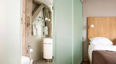 a bedroom with a bed and a bathroom with a sink at Hotel Brosundet in Ålesund