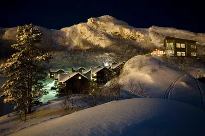 a house covered in snow at night with a mountain at Skarsnuten Mountain Resort & SPA in Hemsedal
