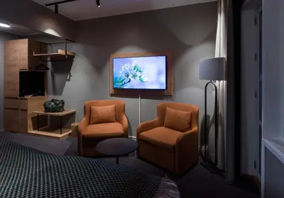 a bedroom with two chairs and a tv on the wall at Skarsnuten Mountain Resort & SPA in Hemsedal