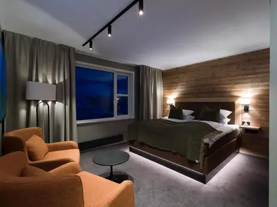 a bedroom with a bed and a chair and a window at Skarsnuten Mountain Resort & SPA in Hemsedal