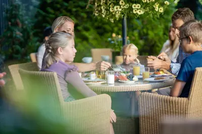 a group of people sitting at a table eating food at Lampeland Hotel in Lampeland