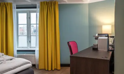 a bedroom with a desk and a window with yellow curtains at Thon Hotel Kristiansund in Kristiansund
