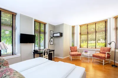 a bedroom with a bed and two chairs and windows at Hotel Park Bergen in Bergen