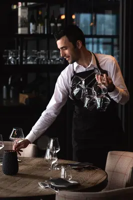 a man standing at a table preparing wine glasses at Vestlia Resort in Geilo
