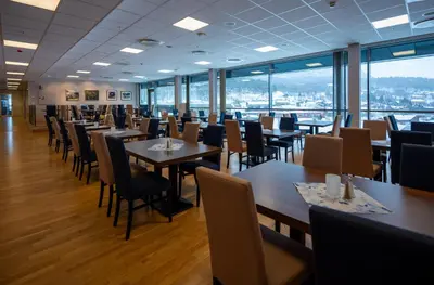 a dining room with tables and chairs and windows at Dombås Hotel in Dombås