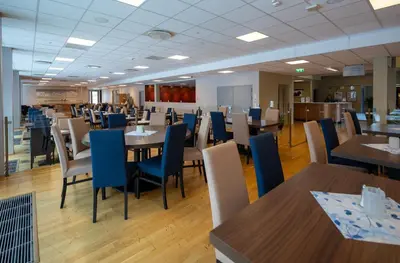 a dining room with tables and blue chairs at Dombås Hotel in Dombås