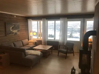 a living room with a couch and a table and windows at Voss Resort self-service apartments in Skulestadmo