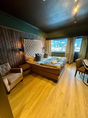 a bedroom with a bed and a chair and a window at Skogstad Hotel - Unike Hoteller in Hemsedal