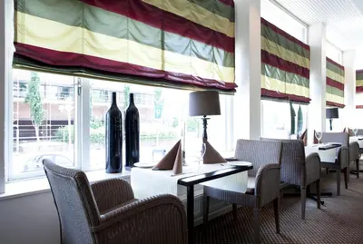 a waiting room with tables and chairs and a large window at Quality Hotel Grand Steinkjer in Steinkjer