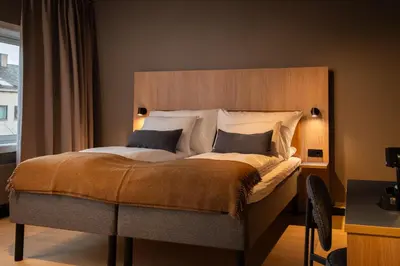 a bedroom with a large bed with a wooden headboard at Quality Hotel Grand Steinkjer in Steinkjer
