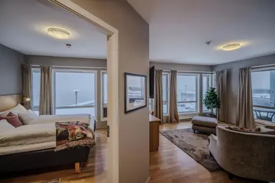 a bedroom with a bed and a living room with windows at Molde Fjordhotell - by Classic Norway Hotels in Molde
