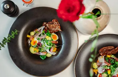 two plates of food on a table with a red rose at Molde Fjordhotell - by Classic Norway Hotels in Molde