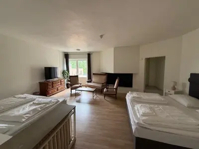 a room with two beds and a couch and a tv at Grand Hotel Hønefoss in Hønefoss