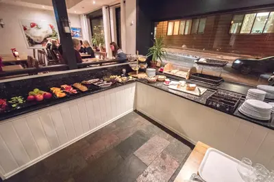 a restaurant with a counter with food on it at Grand Hotel Hønefoss in Hønefoss