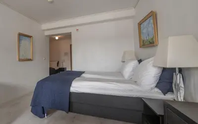 a bedroom with a large bed with a blue blanket at Sunde Fjord Hotel, free and easy parking in Solavagen