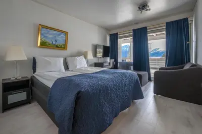 a bedroom with a bed with a blue blanket and a chair at Sunde Fjord Hotel, free and easy parking in Solavagen