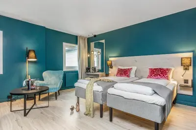 a bedroom with blue walls and a bed and a chair at Thon Hotel Central in Elverum