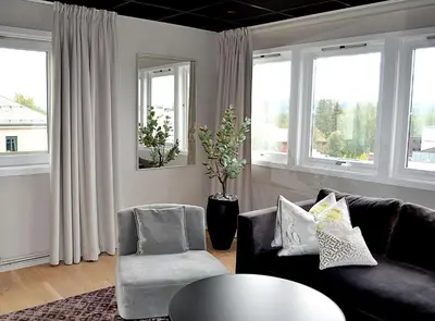 a living room with a couch and a table and windows at Thon Hotel Central in Elverum
