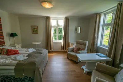 a room with a bed and a couch and a table at Dragsvik Fjordhotel in Balestrand