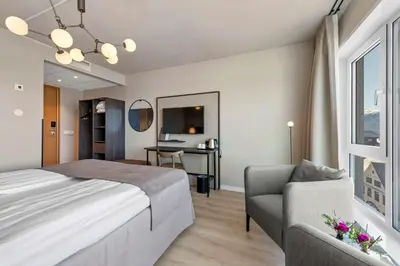 a bedroom with a bed and a chair and a desk at Scandic Parken in Ålesund