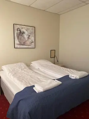 a bed in a room with a painting on the wall at Askvoll Fjordhotell in Ask