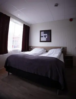 a bedroom with a large bed with a window at Askvoll Fjordhotell in Ask