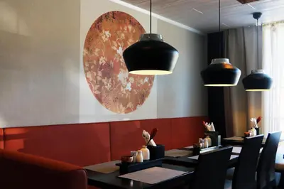a dining room with tables and chairs and pendant lights at Tynset Hotel in Tynset