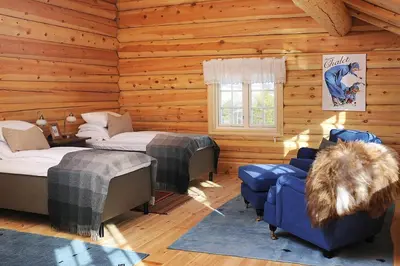 a log cabin with two beds and a couch and a chair at Bjerkeløkkja Bed and Breakfast in Oppdal