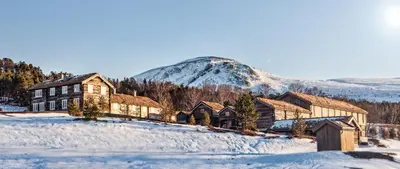 a house in the snow with a mountain in the background at Bjerkeløkkja Bed and Breakfast in Oppdal