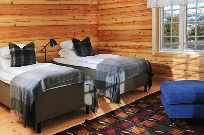 two beds in a room with wooden walls at Bjerkeløkkja Bed and Breakfast in Oppdal