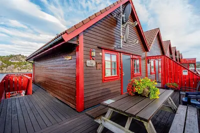 a wooden house with a bench on a deck at Sotra Rorbusenter in Kåravika
