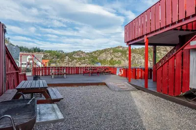 a red building with benches and picnic tables on it at Sotra Rorbusenter in Kåravika