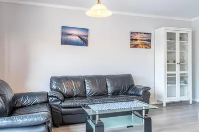 a living room with a leather couch and a table at Sotra Rorbusenter in Kåravika