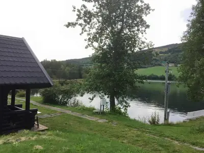 a view of a lake with a tree and a house at Fosheim Hytter in Ron