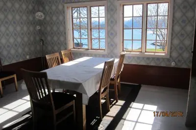 a dining room with a table and chairs and windows at Nicoll-huset in Ølve