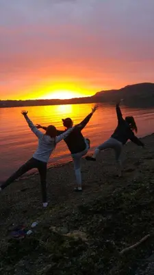 three people doing yoga on the beach at sunset at Strandheimen Guesthouse in Melhus