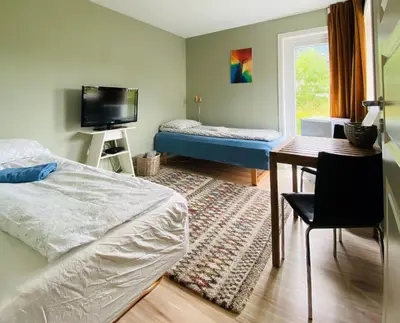a bedroom with a bed and a desk and a window at Strandheimen Guesthouse in Melhus