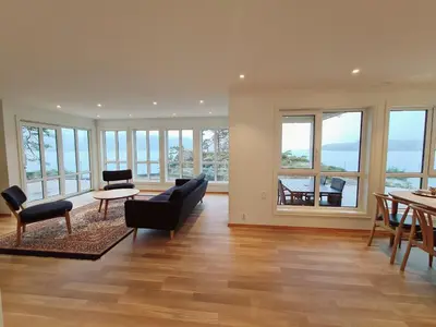 a living room with a couch and chairs and windows at Ropeid Villa Fjordferie in Ropeid