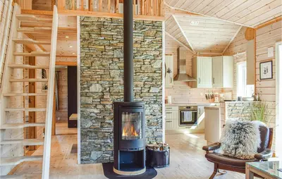 a large stone fireplace in a living room in a log cabin at Tokagjelet in Norheimsund