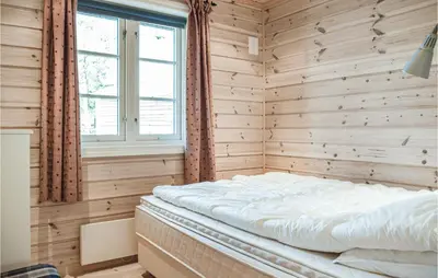 a bed in a wooden room with a window at Tokagjelet in Norheimsund