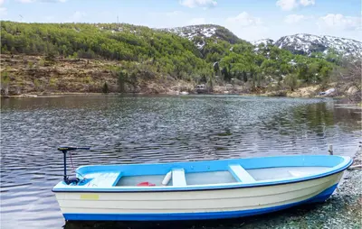 a blue and white boat sitting on a lake at Tokagjelet in Norheimsund