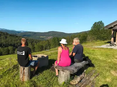 a group of people sitting on a bench on a hill at Tjonnas Farm Stay in Sauland