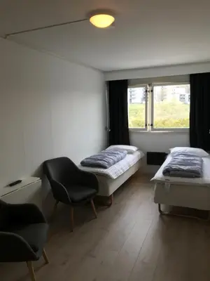 a room with two beds and a chair and a window at Volsdalen Camping in Ålesund
