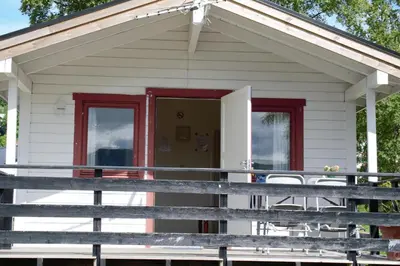 a white house with red doors and a porch at Volsdalen Camping in Ålesund